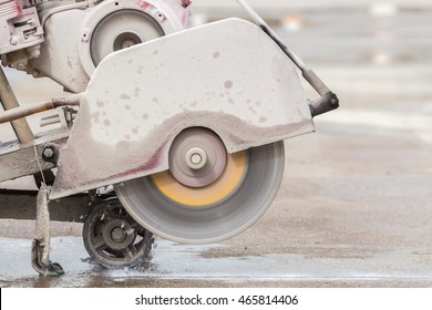 A worker cutting concrete road with diamond saw blade machine