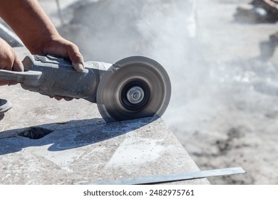 Worker cutting granite slab with angle grinder in construction site - Powered by Shutterstock