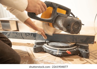 Worker cutting part of furniture with cutting machine.
