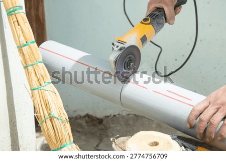 Worker cutting plastic pipe with a electric grinder.
