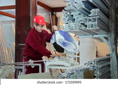 Worker Cutting PVC Profile With Circular Saw. Industrial Equipment. PVC Windows And Doors Manufacturing.