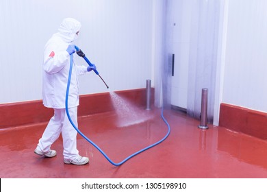 worker of the cutting room washing the cold room with water pressure equipment and dressed in hygienic clothing - Powered by Shutterstock