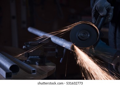 Worker Cutting Steel Pipe With A Electric Rotary Angle Grinder On An Working Table And Generating Sparks