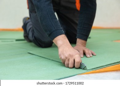 Worker cutting underlayment for flooring - Shutterstock ID 1729511002