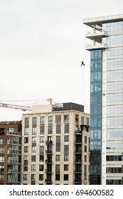 A worker dangles from a safety line while cleaning windows on a skyscraper