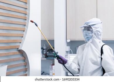 worker from decontamination services wearing personal protective equipment or ppe including white suit mask and face shield spraying disinfectant to cleaning coronavirus infection - Powered by Shutterstock