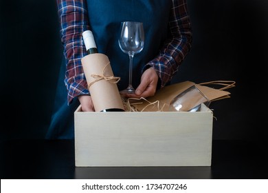 Worker Of Delivery Service Packing Wine Bottle And Glasses To Box With Straw For Customer.