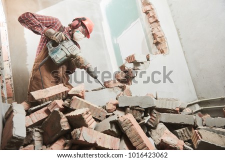worker with demolition hammer breaking interior wall