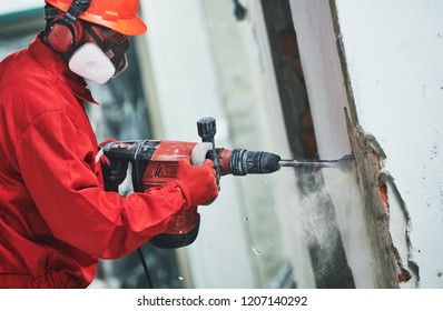 Worker With Demolition Hammer Removing Plaster Or Stucco From Wall