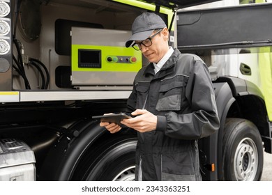 Worker with digital tablet operating construction machine equipment.