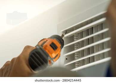 Worker disassembles central air conditioning vent for cleaning and maintenance