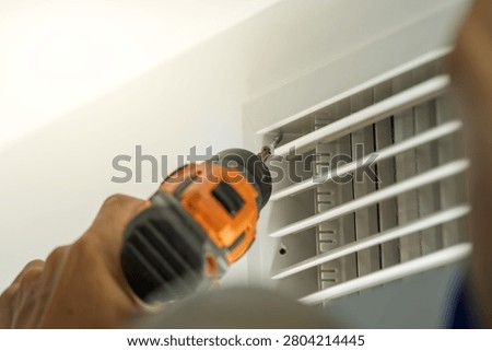 Worker disassembles central air conditioning vent for cleaning and maintenance