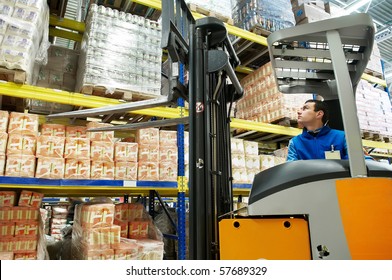 Worker Distributing Goods In A Warehouse With Forklift Truck Loader