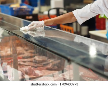 A worker does window disinfection of a butcher shop in a grocery store.