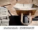 A worker doing paving work throws soil into a construction wheelbarrow with a shovel in his hand. The process of laying paving stones on the pavement.
