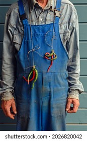 Worker Dressed In Dirty Overalls With A Bunch Of Bitter Pepper Around His Neck. Good Mood