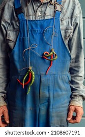 Worker Dressed In Dirty Overalls With A Bunch Of Bitter Pepper Around His Neck. Good Mood.