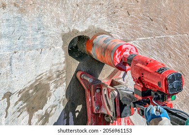 Worker is drilling to concrete wall with core drill machine. Core drills used in metal are called annular cutters. Core drills used for concrete and hard rock generally use industrial diamond grit.