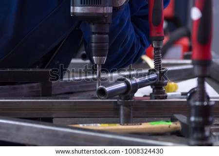 worker drilling a part on a mounting table in the workshop