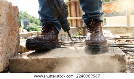 A worker was drilling rocks, and wearing safety shoes to protect his feet