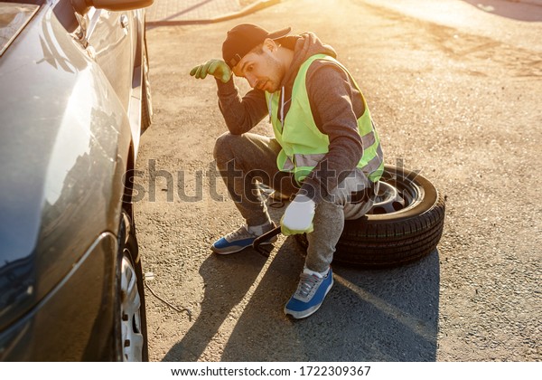 Worker or driver tired of repairing a car on the\
side of the road