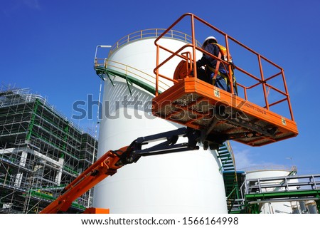 Worker are driving the Orange articulate boom lift or telescopic boom lifts and bucket crane mounted on truck to safety for working at heights and articulating boom lift reaching high up.