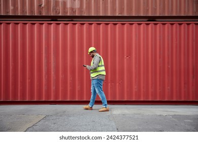 worker or engineer walking forward and working on tablet in containers warehouse storage