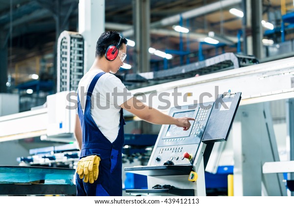 Worker entering data in CNC machine at factory\
floor to get the production\
going