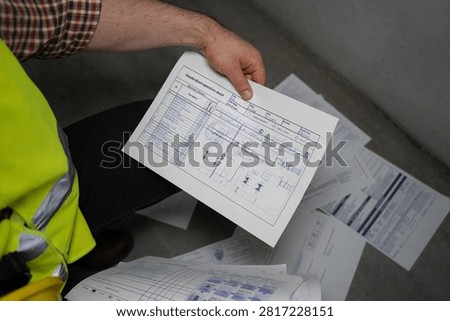 Worker examining technical schematic in industrial setting