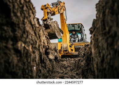 A worker in excavator is moving earth and making foundation at construction site. - Powered by Shutterstock