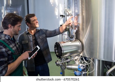 Worker explaining to coworker using tablet computer at brewery - Powered by Shutterstock