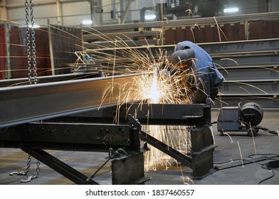 A Worker In A Factory Is Cleaning The Steel Structure Of An Angle Grinder In A Workshop. Sparks