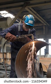 worker in factory cutting steel pipe using metal torch