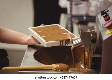 Worker filling mould with melted chocolate in kitchen - Powered by Shutterstock