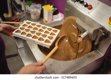 Worker filling mould with melted chocolate in kitchen - Powered by Shutterstock