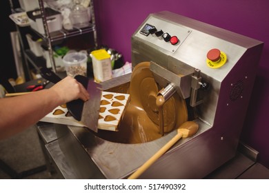 Worker filling mould with melted chocolate in kitchen - Powered by Shutterstock