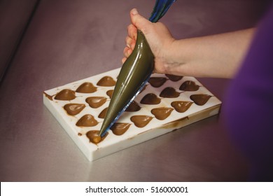 Worker filling mould with piping bag in kitchen - Powered by Shutterstock