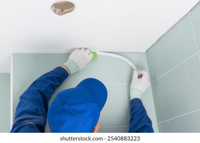 worker finishes installing stretch ceiling in bathroom