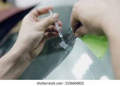 Worker Fixes Crack In Car Glass Windshield, Repair Drills And Pours Epoxy.