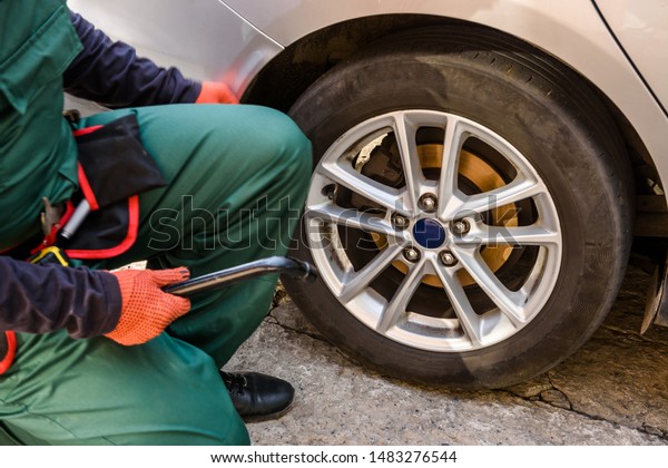 Worker fixing car\
wheel with spanner close\
up