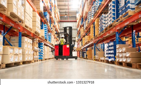 Worker in forklift-truck loading packed goods in huge distribution warehouse with high shelves. - Powered by Shutterstock