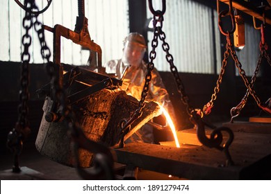 Worker in foundry pouring hot metal into mold. Molten iron casting production and metallurgy. - Powered by Shutterstock