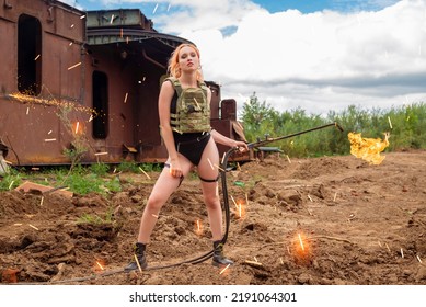 A Worker Girl In A Bulletproof Vest And A Black Bodysuit Holds A Thermal Lance. Hot Woman In Sparks With Flames. The Concept Of Feminism. Man Tools In Female Hands.