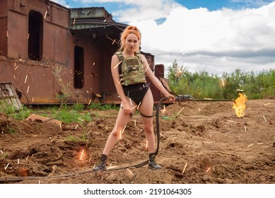 A Worker Girl In A Bulletproof Vest And A Black Bodysuit Holds A Thermal Lance. Hot Woman In Sparks With Flames. The Concept Of Feminism. Man Tools In Female Hands.