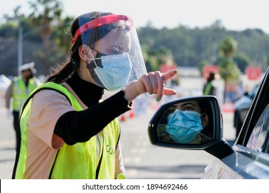 A Worker Gives Directions To Motorist As She Waits In Lines To Get The Coronavirus (COVID-19) Vaccine In A Parking Lot At Dodger Stadium, Friday, Jan. 15, 2021, In Los Angeles. 