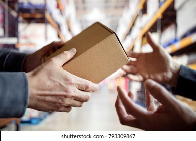 Worker giving a package in distribution warehouse