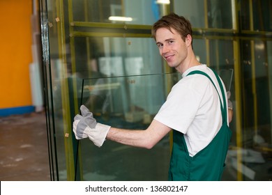 Worker in glazier's workshop, warehouse  or storage handling glass