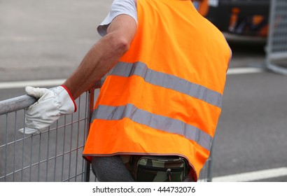 worker with gloves moves iron hurdles after the sporting event on the road