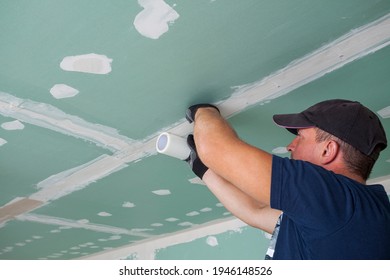Worker glues mesh to drywall seams 