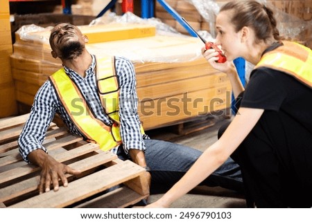 Worker got an accident while working inside the warehouse and his or her colleague quickly running to assist and call for emergency support. Warehouse worker have an accident during working.